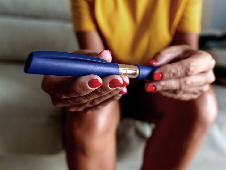 A woman sits on a sofa while holding a semaglutide injection, a GLP-1 agonst used to treat type 2 diabetes and aid weight loss